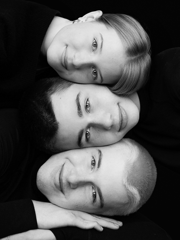 Creatief kinderportret drie kinderhoofden liggend op elkaar tegen een zwarte achtergrond 01